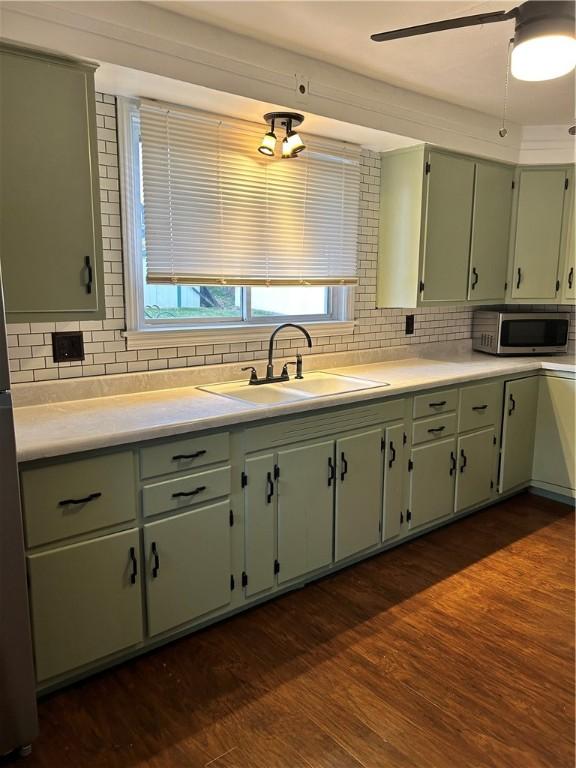 kitchen with backsplash, dark hardwood / wood-style floors, green cabinetry, and sink