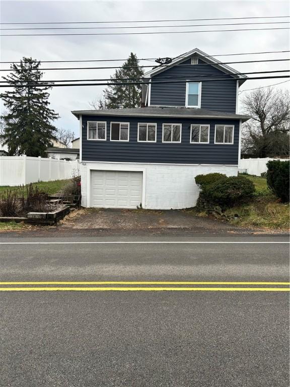 view of front facade featuring an attached garage, driveway, and fence