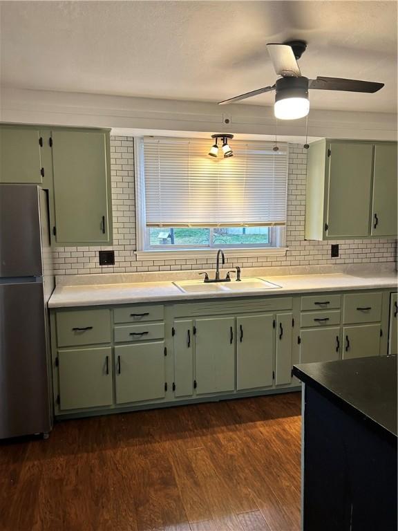 kitchen with dark hardwood / wood-style flooring, stainless steel fridge, green cabinets, and sink