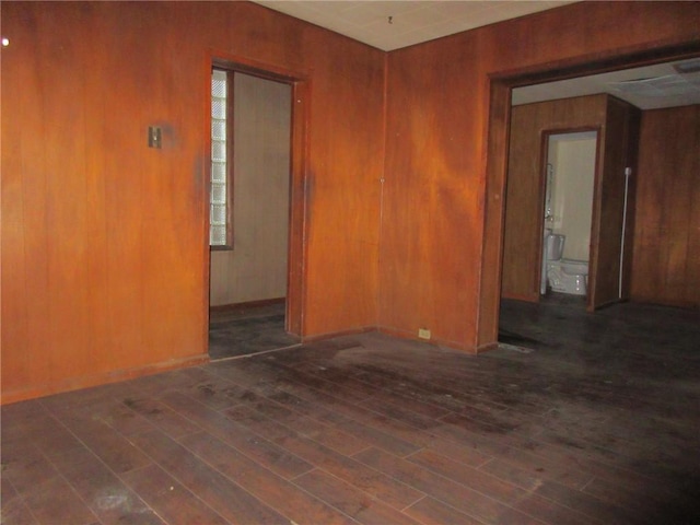 unfurnished room with dark wood-type flooring and wood walls