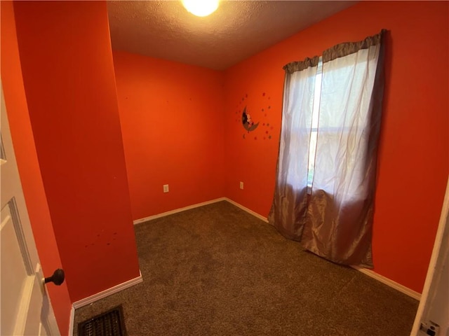 unfurnished room featuring carpet flooring and a textured ceiling