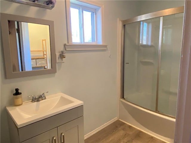 bathroom featuring hardwood / wood-style floors, vanity, and enclosed tub / shower combo