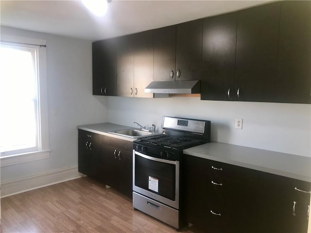 kitchen with light wood-type flooring, stainless steel gas stove, and sink