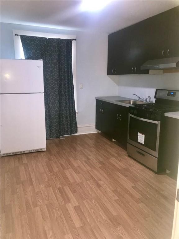 kitchen featuring sink, light hardwood / wood-style flooring, stainless steel range oven, and white refrigerator