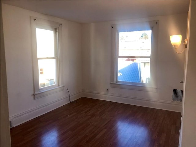 empty room featuring plenty of natural light and dark hardwood / wood-style flooring