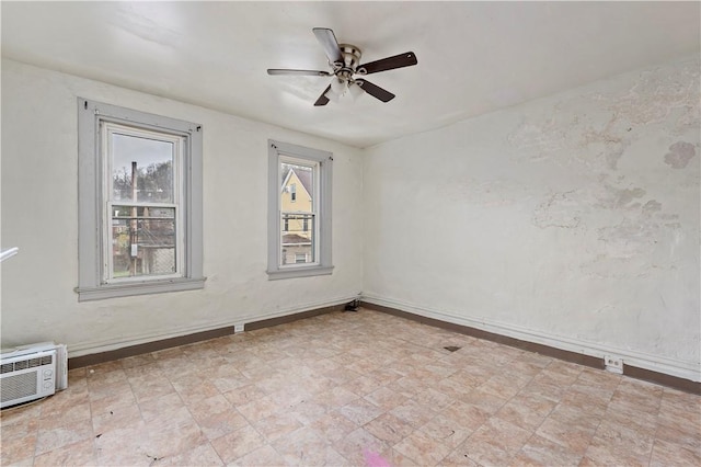 empty room featuring a wall mounted AC, baseboards, and ceiling fan