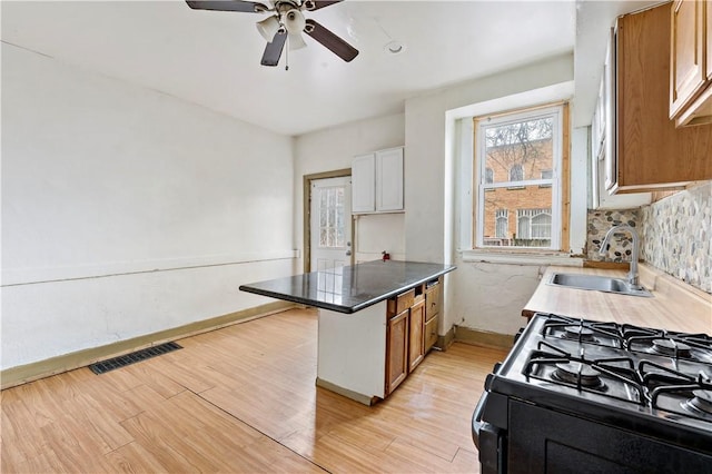 kitchen with visible vents, black range with gas cooktop, a sink, ceiling fan, and light wood finished floors