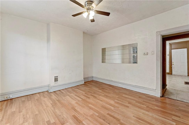 unfurnished room featuring a textured ceiling, a ceiling fan, visible vents, wood finished floors, and baseboards