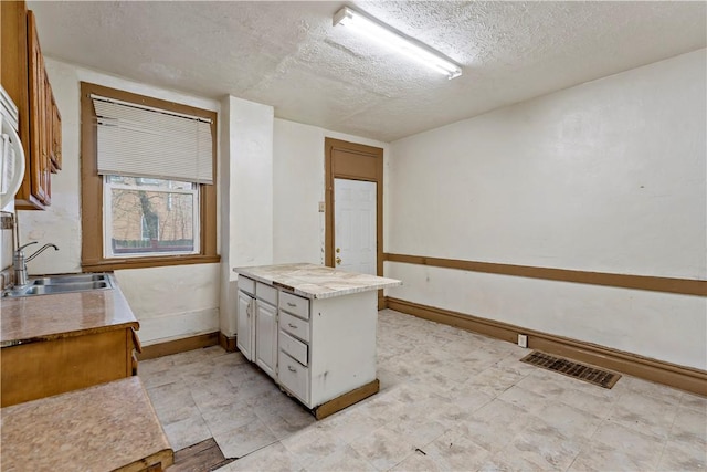 interior space with baseboards, visible vents, a textured ceiling, and a sink