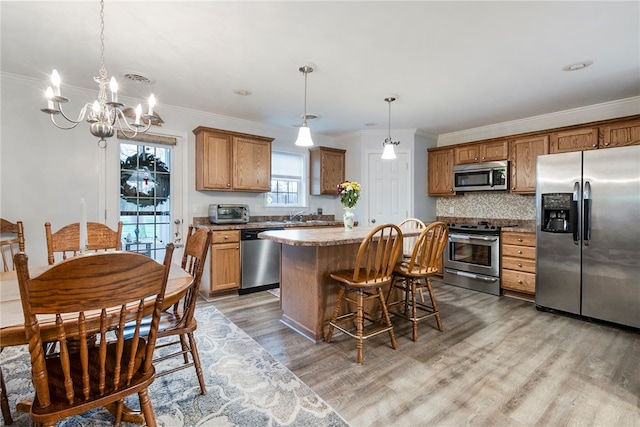 kitchen with a center island, hanging light fixtures, stainless steel appliances, a chandelier, and light wood-type flooring