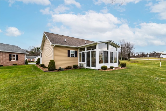 back of property featuring a sunroom and a lawn