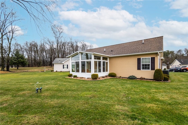 rear view of property with a lawn and a sunroom