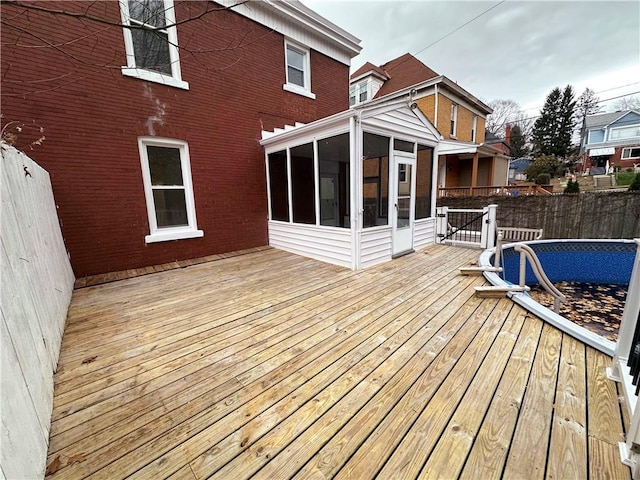 wooden terrace featuring a sunroom and a fenced in pool