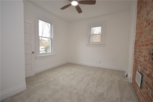 spare room with ceiling fan, brick wall, light carpet, and a wealth of natural light