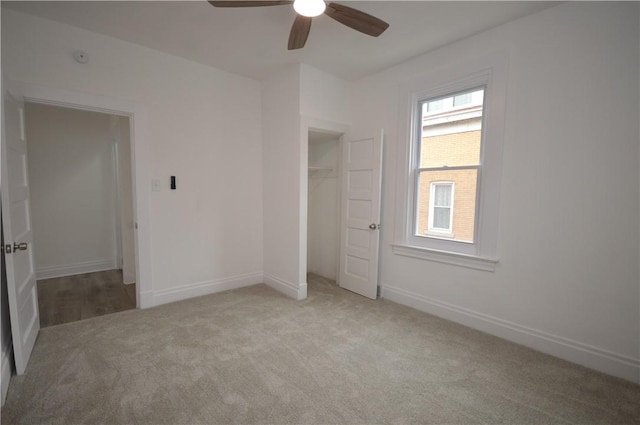 unfurnished bedroom with ceiling fan, a closet, light colored carpet, and a spacious closet