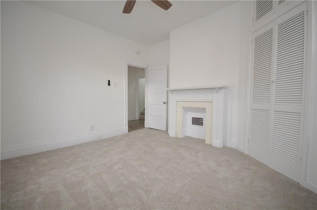 unfurnished living room with ceiling fan, a fireplace, and light colored carpet