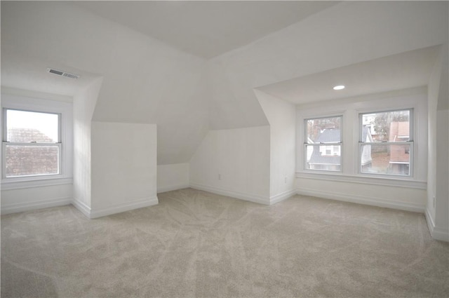 additional living space featuring light carpet and vaulted ceiling