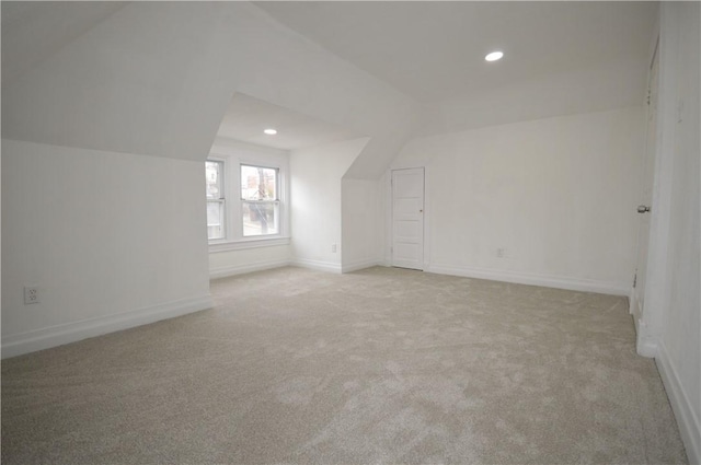 bonus room with light colored carpet and vaulted ceiling