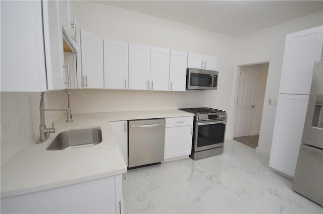 kitchen with white cabinets, appliances with stainless steel finishes, decorative backsplash, and sink