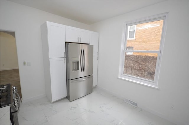 kitchen featuring white cabinetry, stainless steel refrigerator with ice dispenser, and range