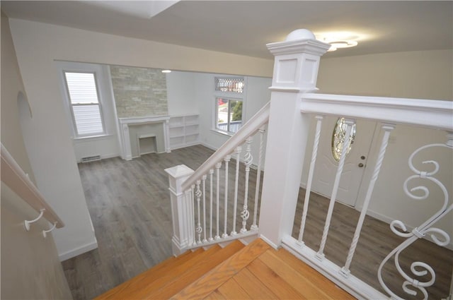 staircase with hardwood / wood-style flooring and a large fireplace