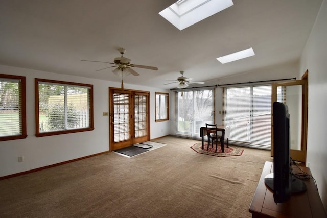 unfurnished sunroom featuring carpet floors, vaulted ceiling with skylight, and ceiling fan