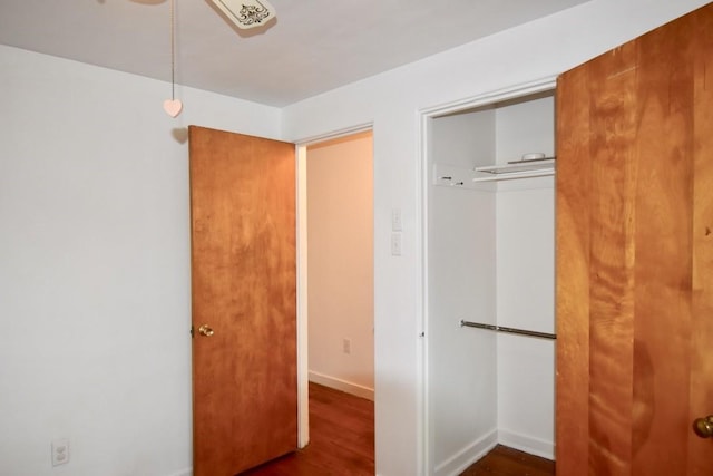 unfurnished bedroom with dark hardwood / wood-style flooring and a closet