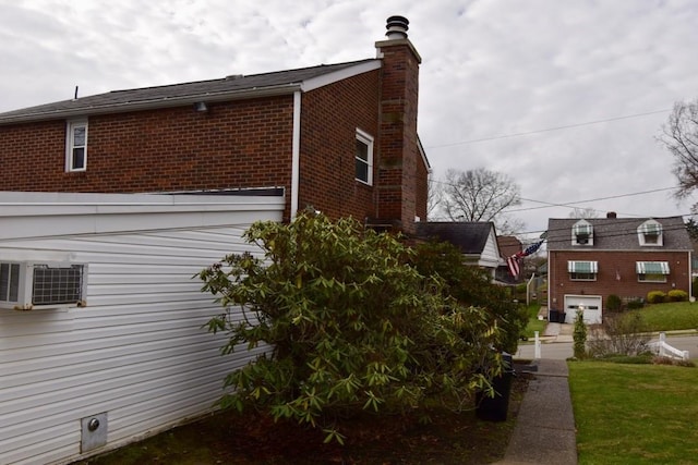 view of property exterior featuring a garage, cooling unit, and a lawn