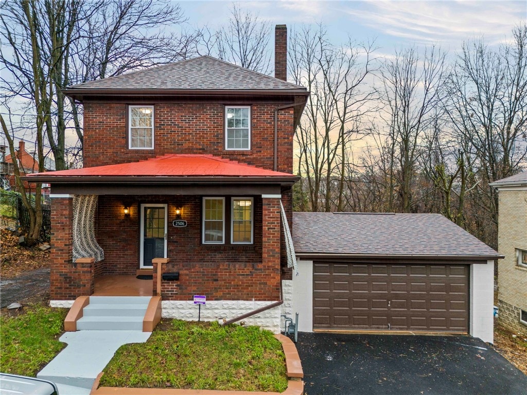 front facade with a porch, a garage, and an outdoor structure