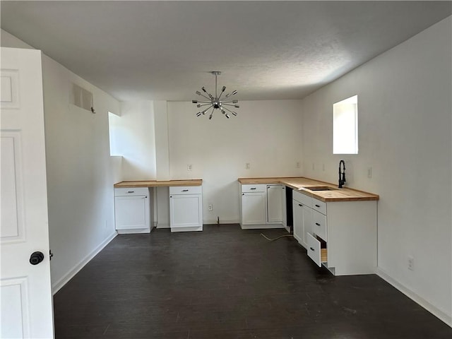 kitchen with white cabinets, sink, dark hardwood / wood-style floors, butcher block counters, and a chandelier