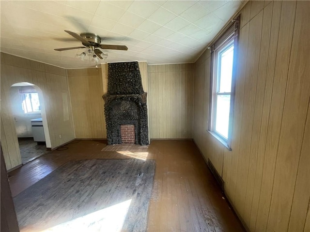 unfurnished living room with a large fireplace, dark wood-type flooring, ceiling fan, and a healthy amount of sunlight