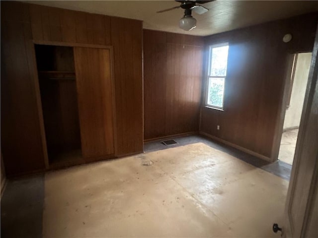 unfurnished bedroom with wood walls, a closet, and ceiling fan