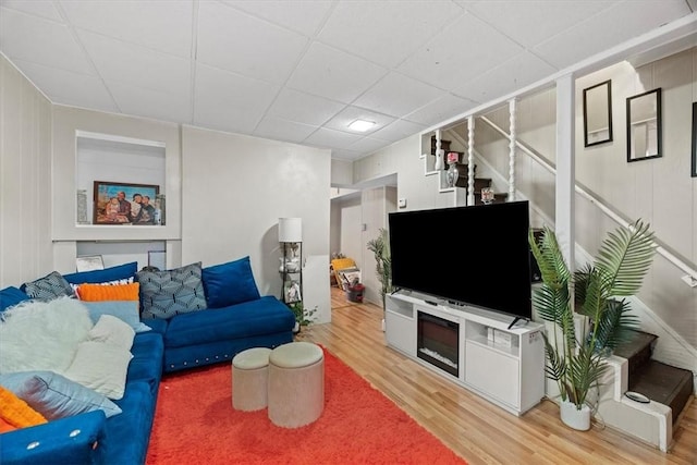 living room featuring wood-type flooring and a drop ceiling