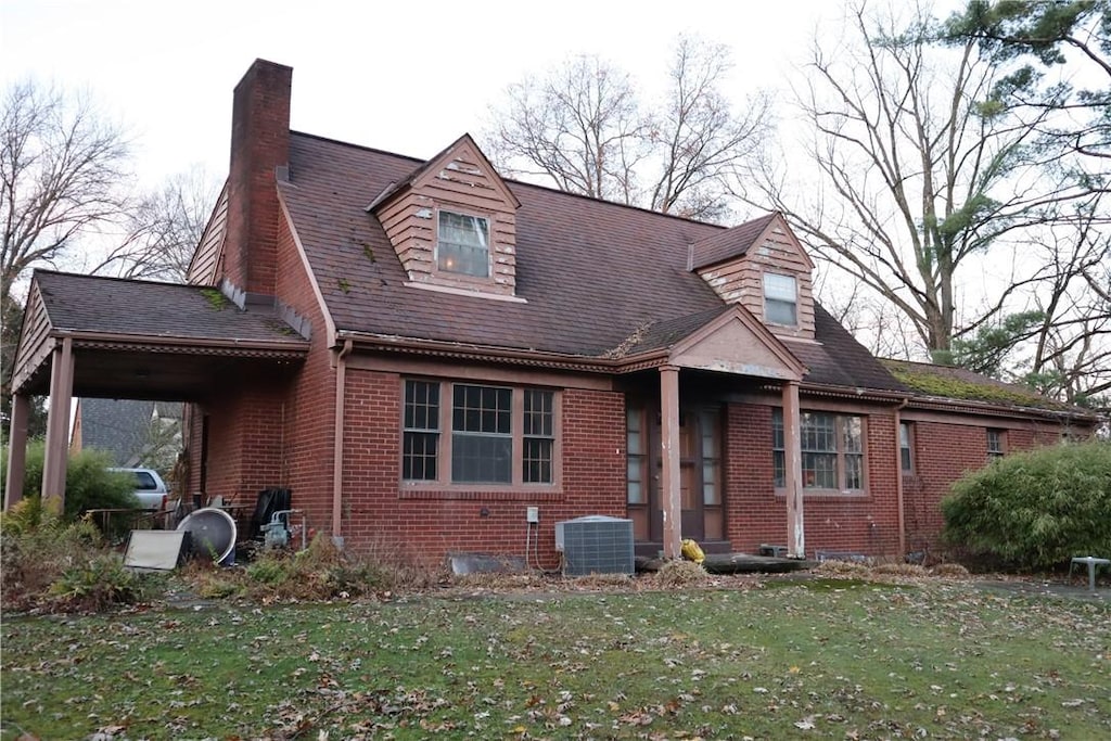 view of front of home with a front yard and central AC