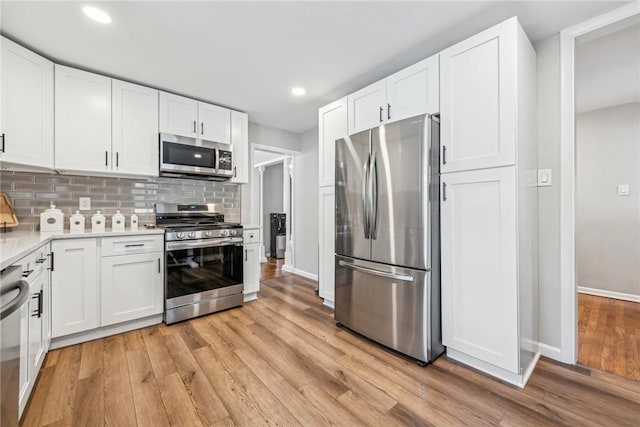 kitchen featuring white cabinets, light wood-type flooring, stainless steel appliances, and tasteful backsplash