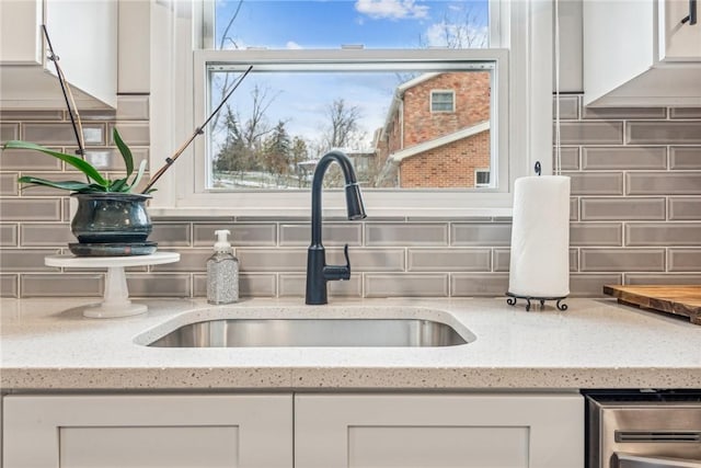 details featuring white cabinets, sink, and tasteful backsplash