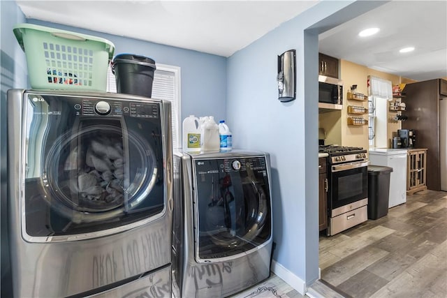 clothes washing area with wood-type flooring and washing machine and clothes dryer