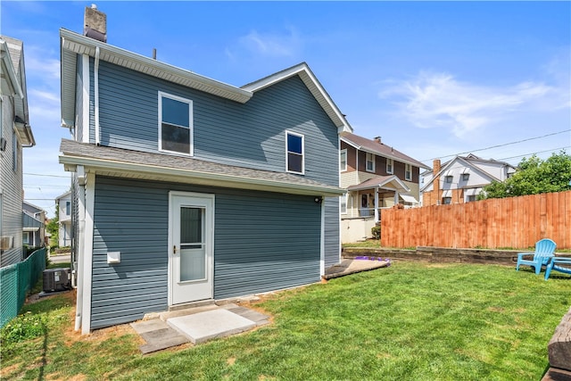 rear view of house with a lawn and central AC unit