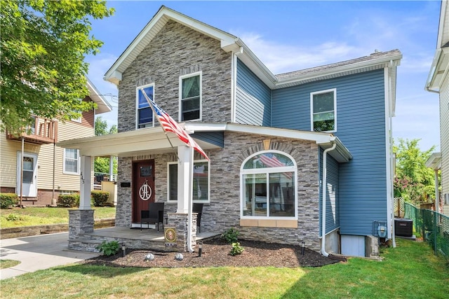 view of front of home with a porch, a front yard, and central AC