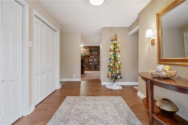 hallway featuring hardwood / wood-style flooring and brick wall