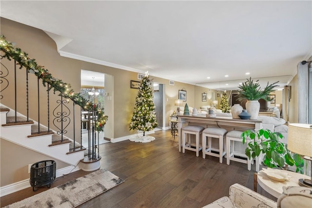 living room with dark hardwood / wood-style floors, an inviting chandelier, and ornamental molding