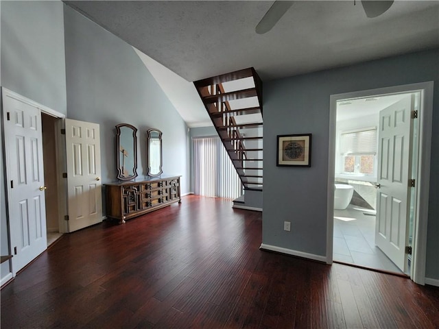 unfurnished living room with ceiling fan, dark hardwood / wood-style floors, and high vaulted ceiling