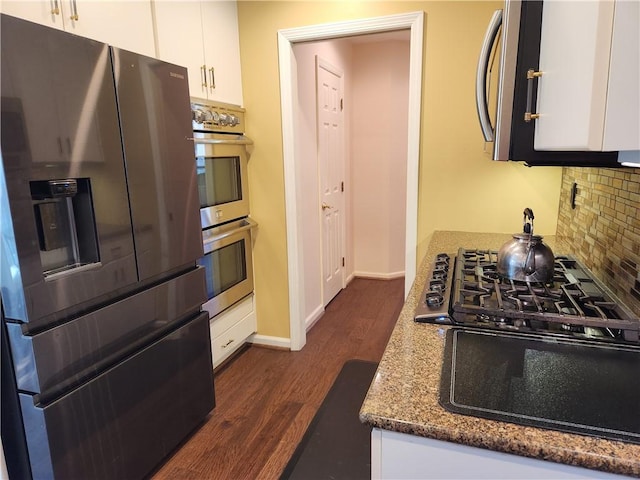 kitchen with tasteful backsplash, white cabinetry, dark stone counters, stainless steel double oven, and fridge with ice dispenser