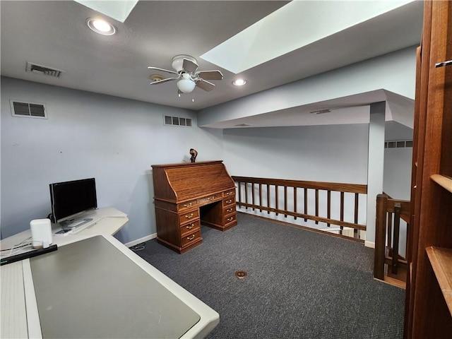 office area with ceiling fan, a skylight, and dark colored carpet