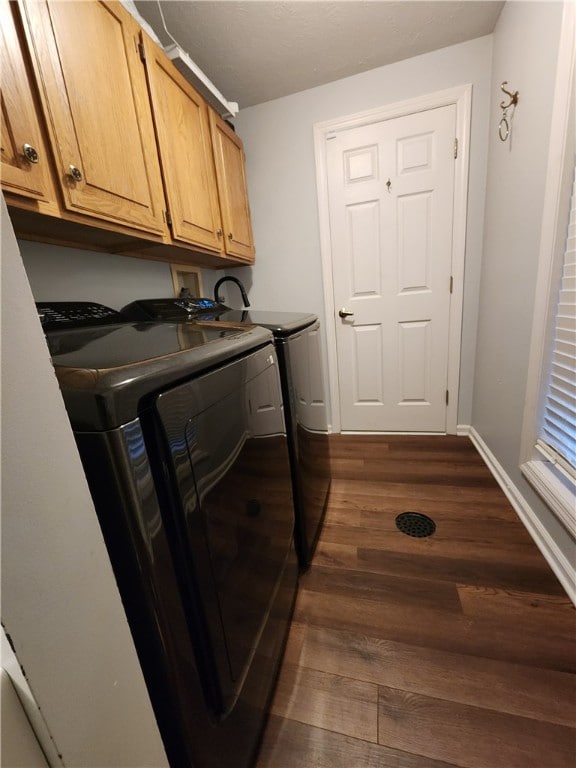 clothes washing area featuring dark hardwood / wood-style flooring, cabinets, and independent washer and dryer