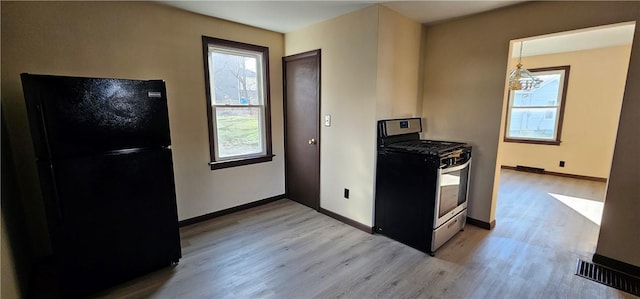 kitchen with visible vents, a healthy amount of sunlight, stainless steel range with gas cooktop, light wood-type flooring, and freestanding refrigerator