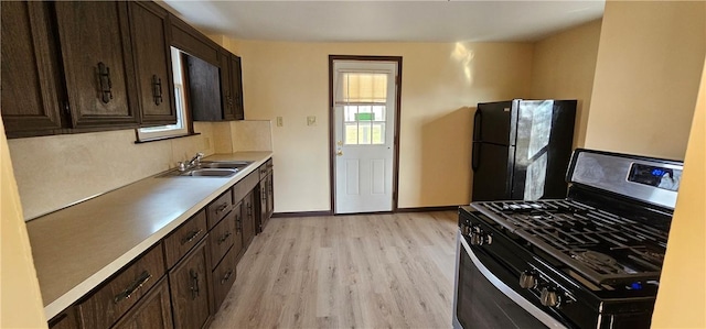 kitchen with black appliances, dark brown cabinets, light wood-type flooring, and sink