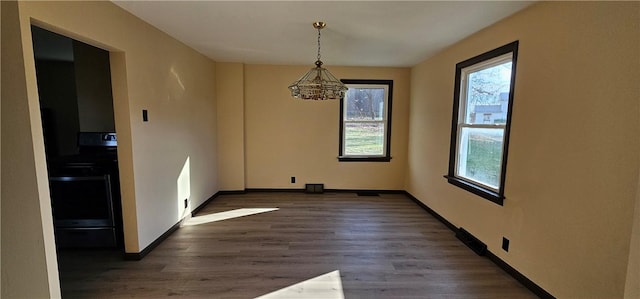 unfurnished dining area with a notable chandelier and dark wood-type flooring