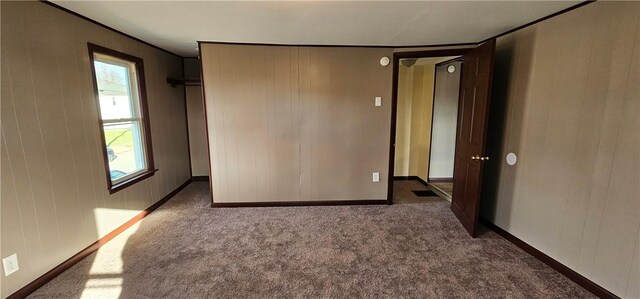 unfurnished room featuring wooden walls and dark carpet