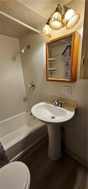 bathroom with a textured ceiling, hardwood / wood-style flooring, toilet, and shower / bathtub combination with curtain